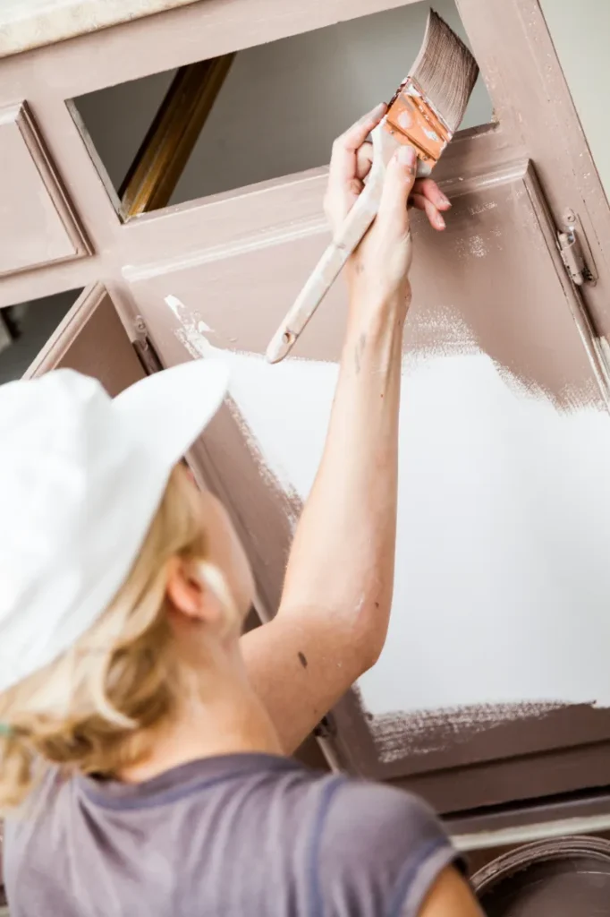 Applying paint to cabinet doors during a cabinet painting project.